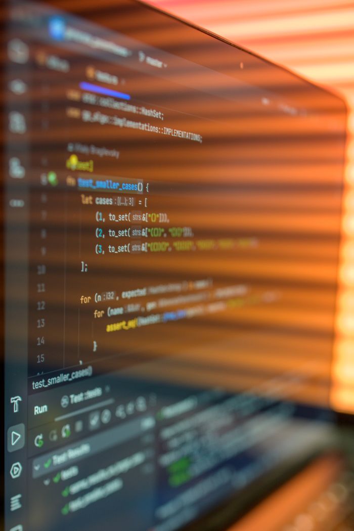 services-01 Close-up image of a computer screen displaying colorful programming code in a warm setting.