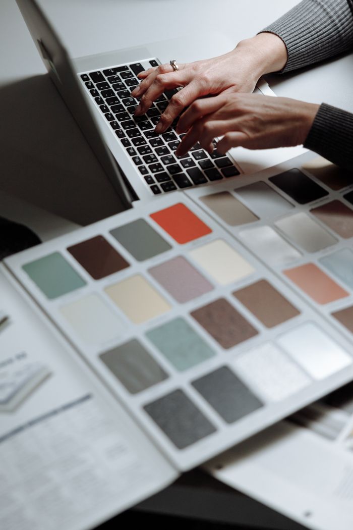 Crafting Captivating Headlines: Your awesome post title goes here Hands typing on a laptop next to a color swatch book, ideal for design and creativity themes.